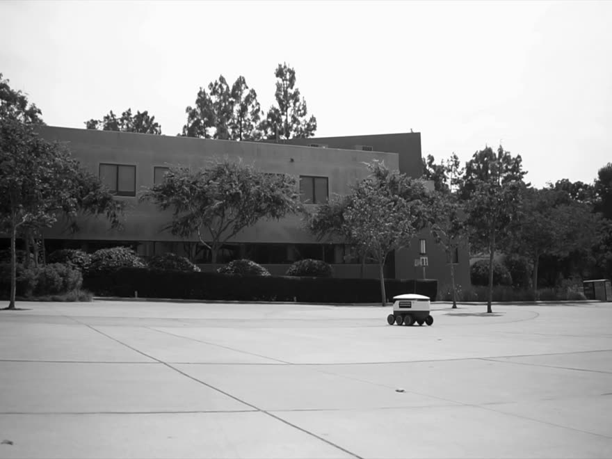 A small delivery robot crossing an empty plaza